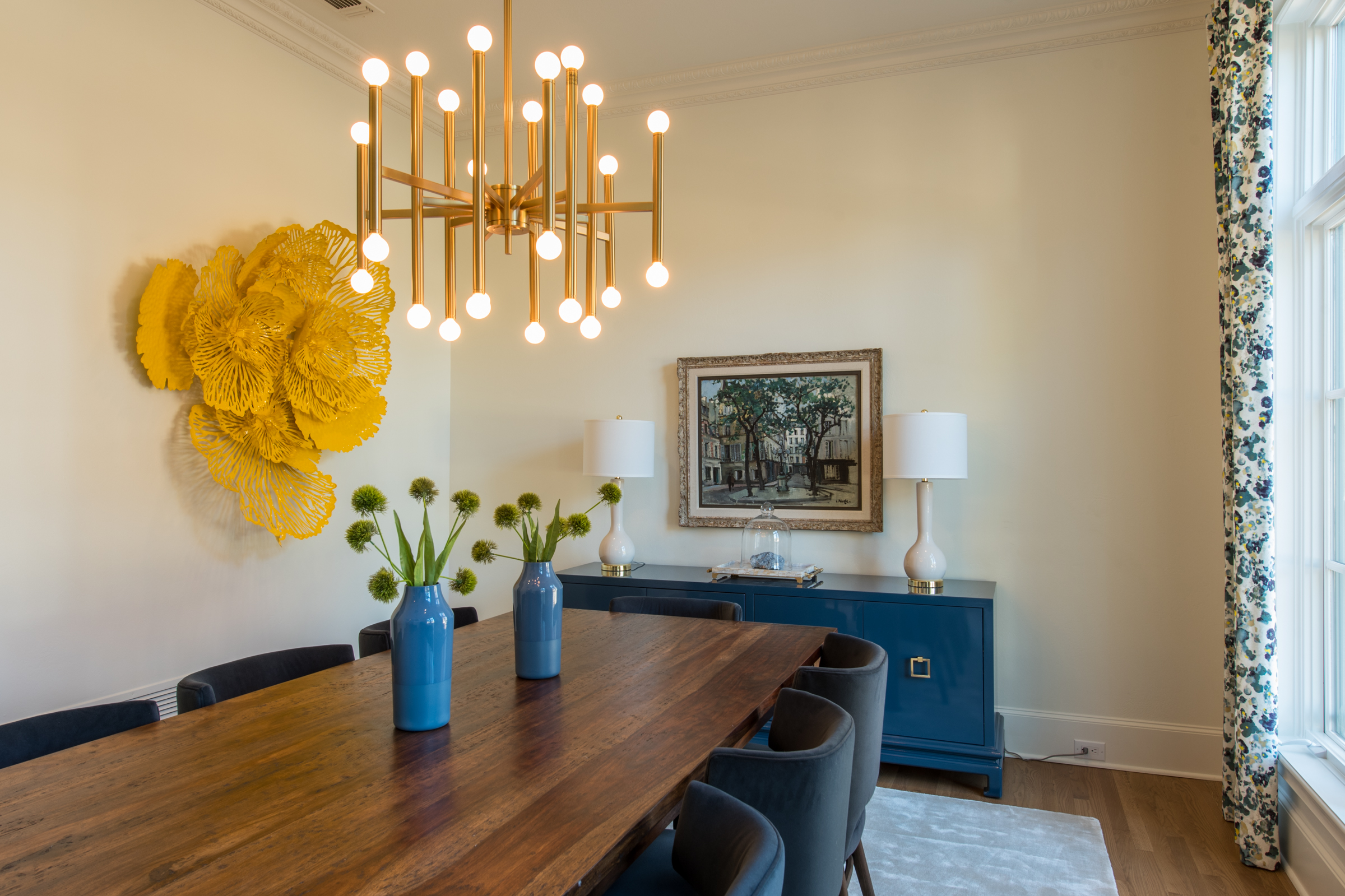 Dining room with yellow art and modern chandelier